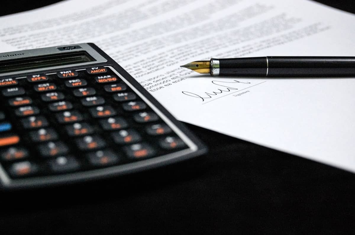 Calculator, document și stilou - simboluri ale calculului și semnării unei polițe de asigurare.