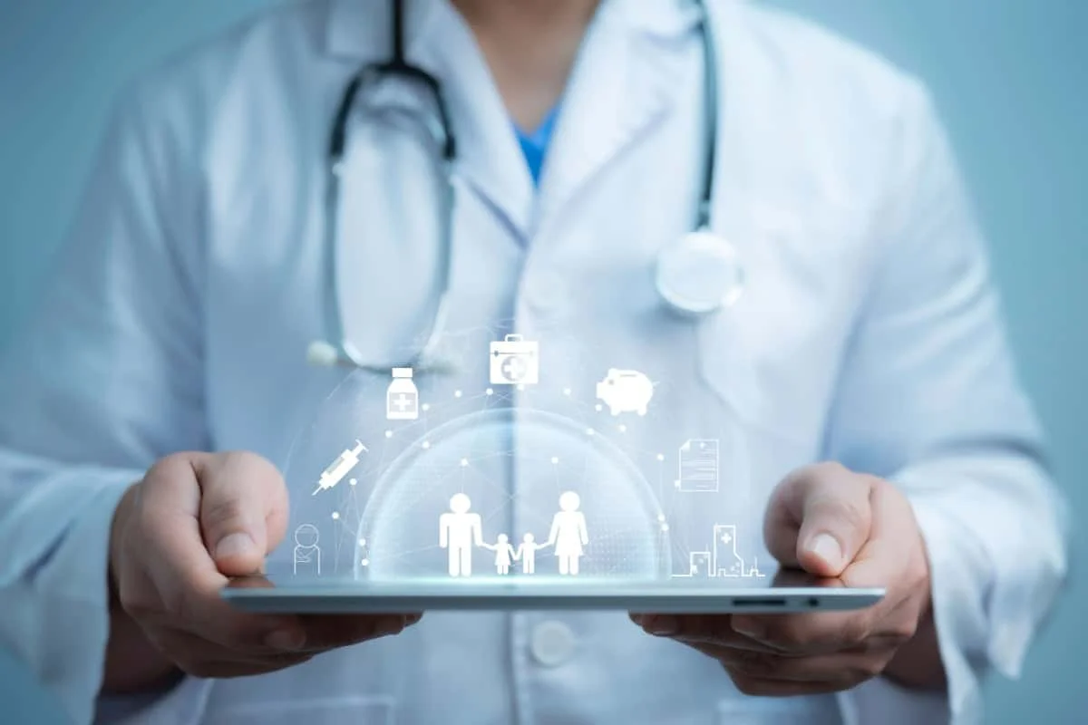 Medic in halat alb tine o tableta cu simboluri digitale legate de sanatate si familie