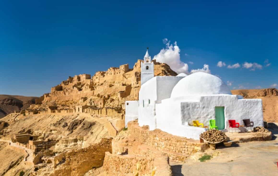 Satul Matmata casa alba pe dealuri stancoase cu scaune colorate si vedere spectaculoasa spre ruinele de sus