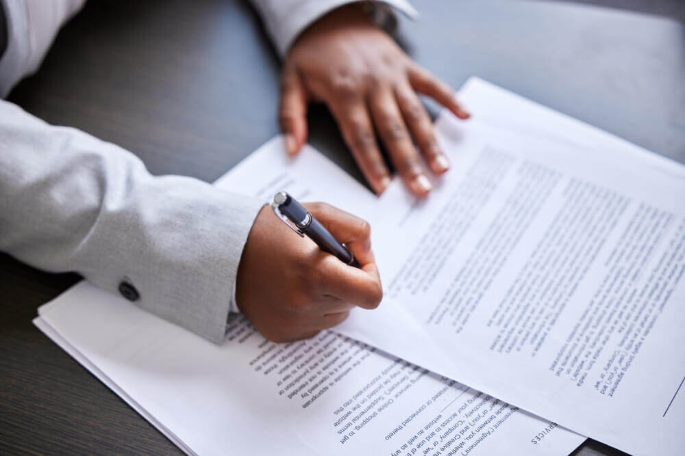 Mainile unei persoane care semneaza un contract de asigurare intr-un birou