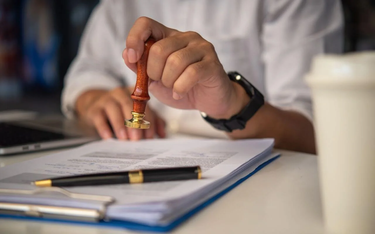 O persoana aplica o stampila pe un document oficial