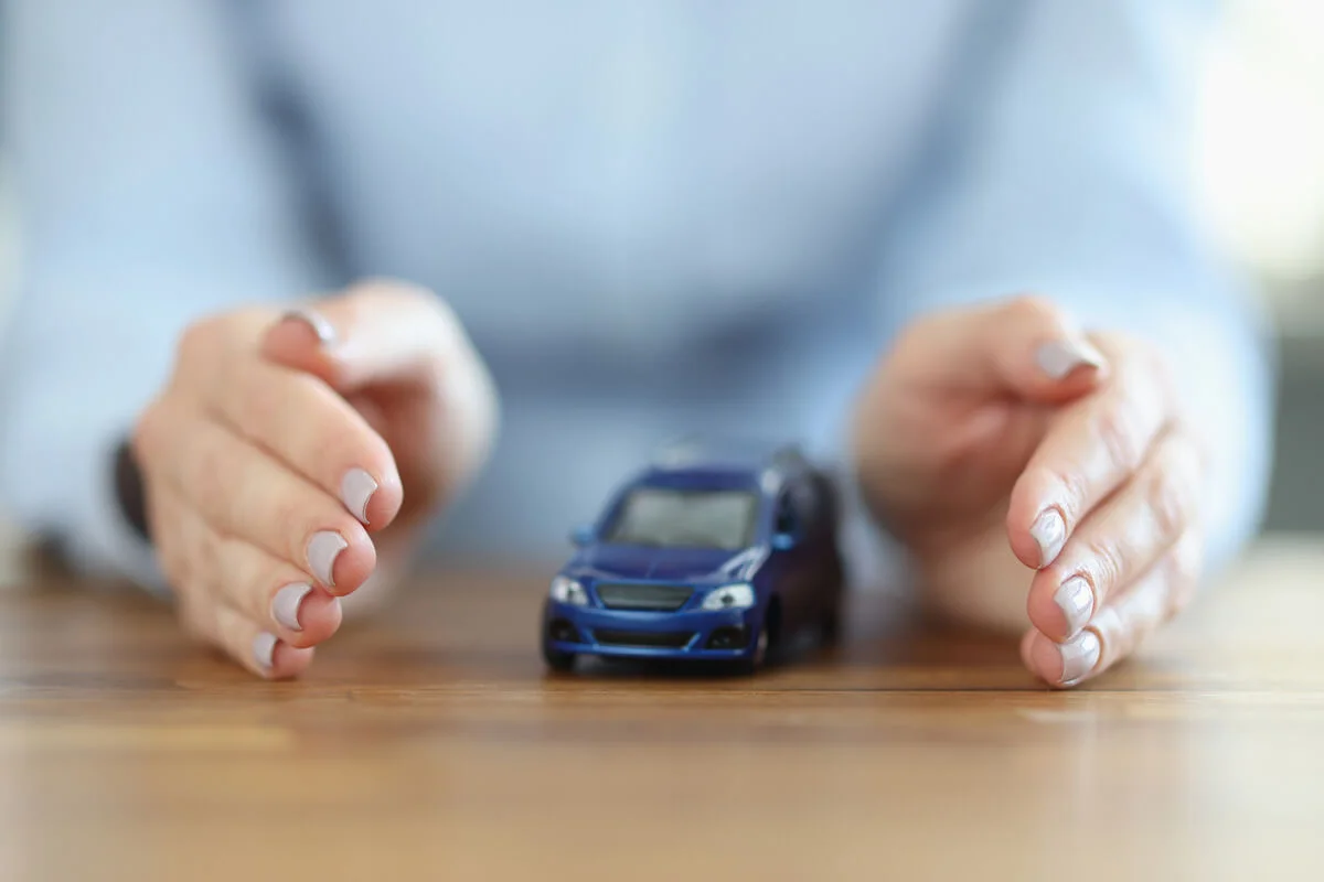 Mâinile unui bărbat înconjurând o machetă de autoturism pe un birou