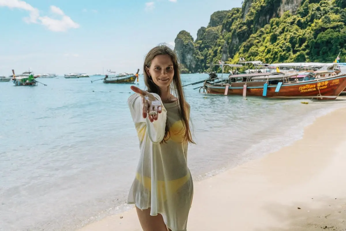 Turistă pe plaja din Thailanda cu bărci tradiționale în fundal